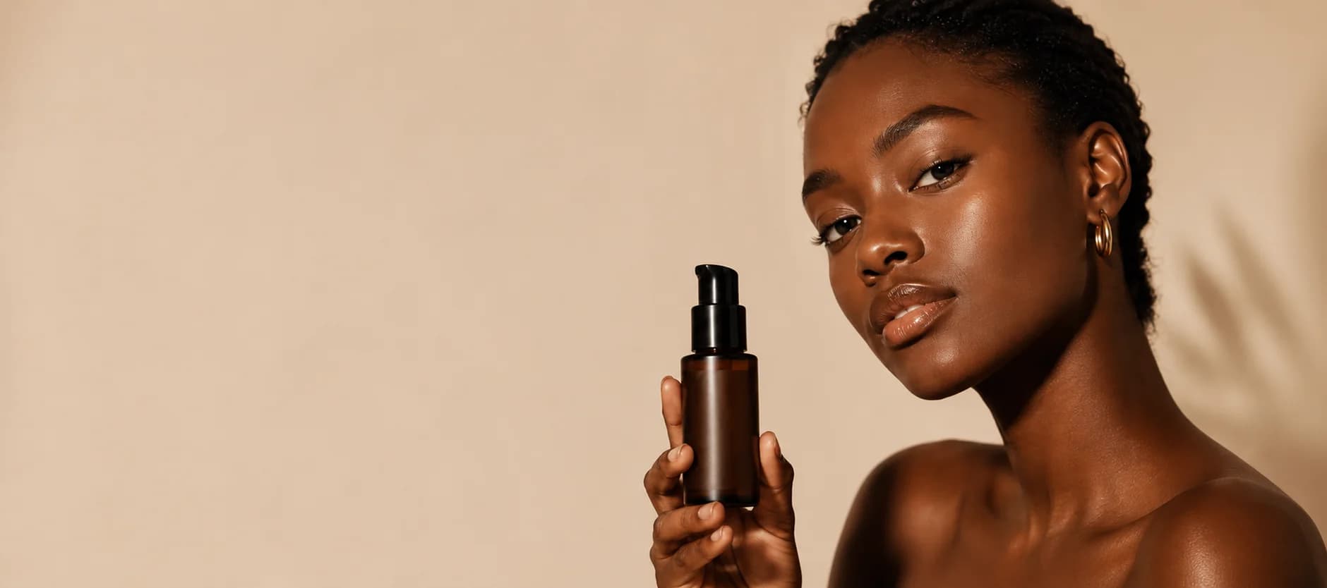 Femme à la peau riche en mélanine tenant un flacon de sérum